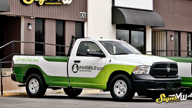 Pickup truck in the foreground of the photo with a full wrap for Invisible Waste Services