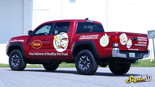 Pickup truck in the foreground of the photo with a full wrap for Husse Pet Food